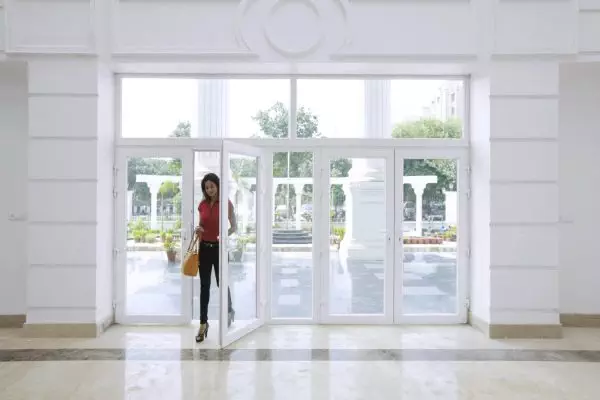 A woman standing in front of an open door showcasing Forever Green Windows.